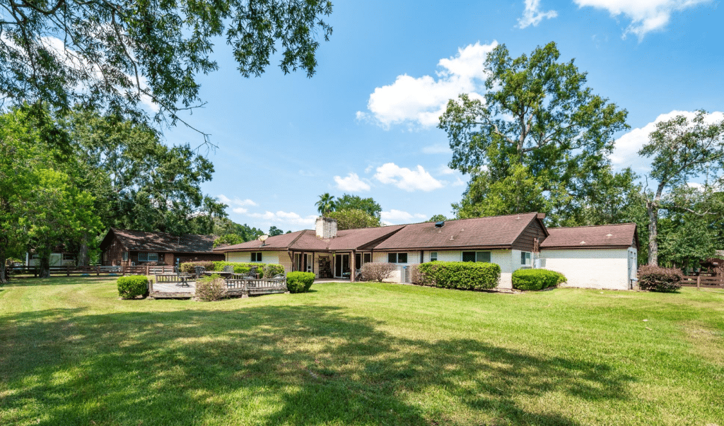 Exterior of a home for sale in Conroe, TX showing large lot and mature trees.