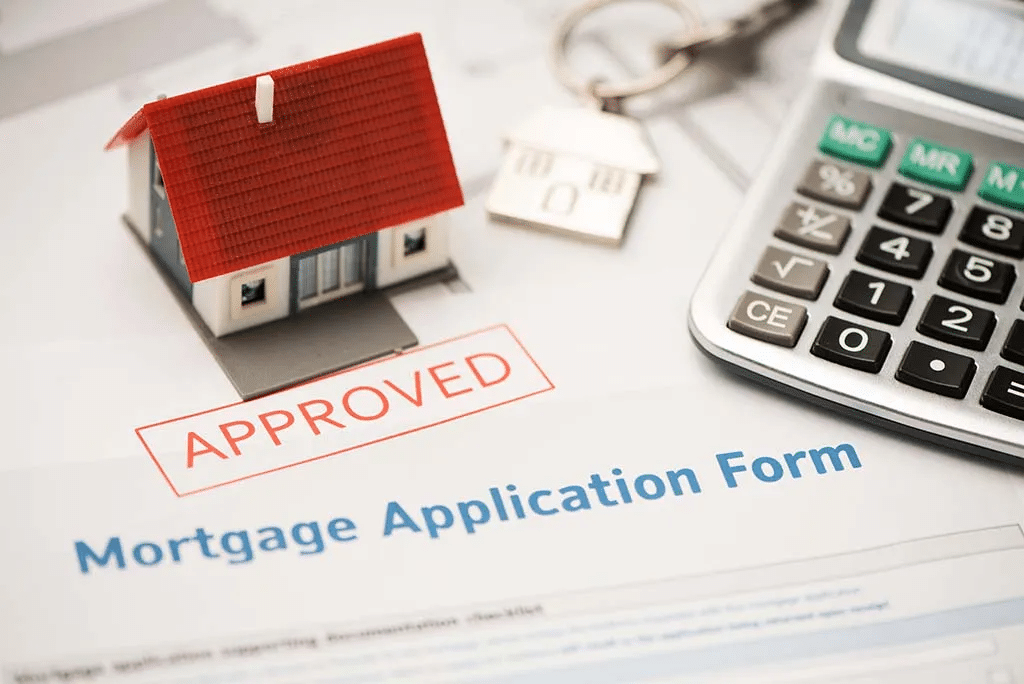 Mortgage application form stamped ‘Approved’ beside a calculator, house model, and house key keychain, representing home loan approval and the home buying process in Montgomery County, TX.