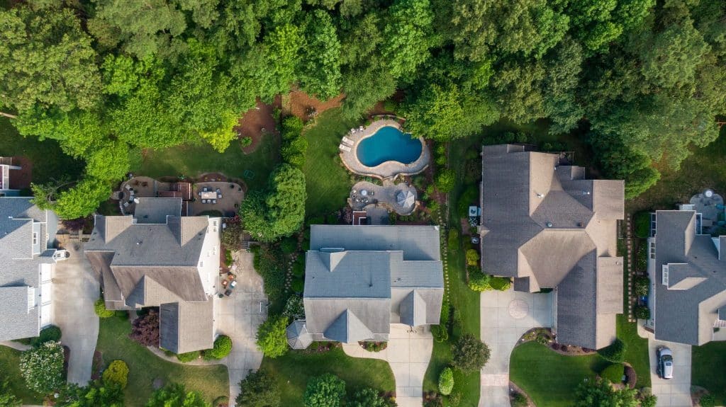 Aerial view of a house with a pool in a neighborhood.
